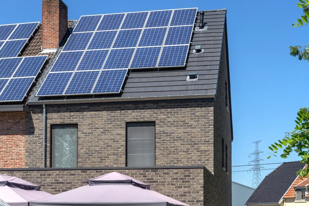 A brick home with solar panels fitted to the roof and a parasol on the terrace.