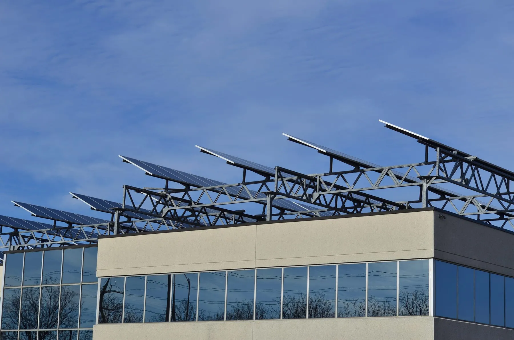 Rows of solar panels raised on steel frames above the roof of a commercial building.