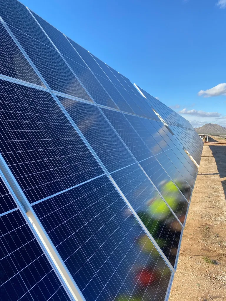 A solar panel angled against an open sky, the glass reflecting cloud.